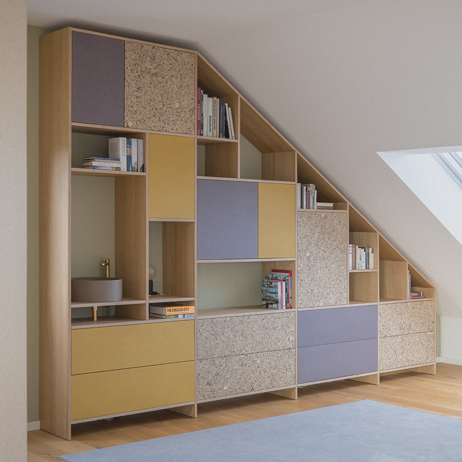„Maßgefertigtes, modernes Regal und Stauraumlösung unter einer Dachschräge mit bunten Fronten und Holzstruktur – individuelles Möbelunikat im hochwertigen Innenausbau.“ Maßgefertigtes Möbel unter Dachschräge