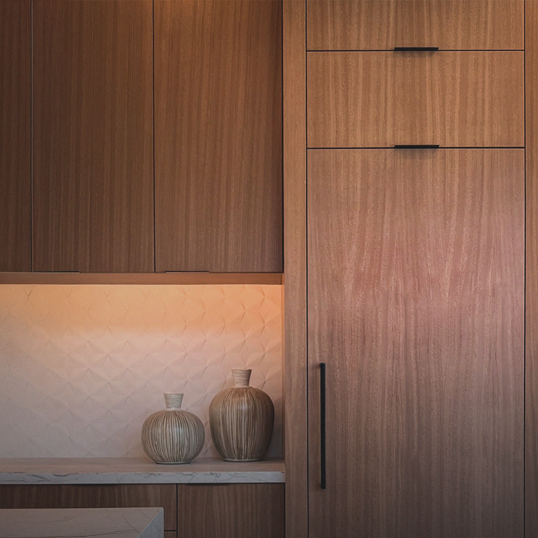„Edle Küchenfronten aus warmem Holz mit feiner Maserung, stimmig beleuchtete Arbeitsfläche und hochwertige Materialien – modernes, maßgefertigtes Möbeldesign im Premium-Innenausbau.“ Schreinerküche
